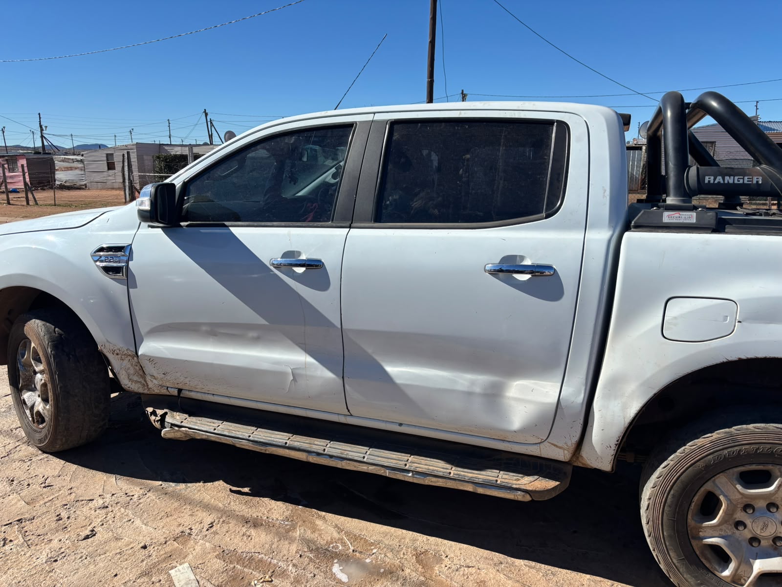Side profile of a white Ford Ranger showing door damage